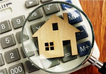 House valuation with calculator and magnifying glass representing real estate mortgage and property finance